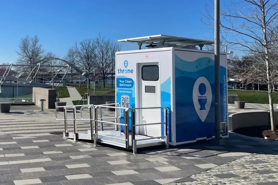Blue and white Throne portable bathroom in an outdoor location.